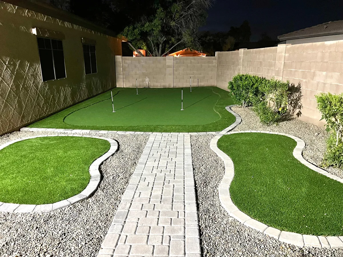 This image highlights a well-maintained putting green bordered by landscaped pathways and lush edges, inviting guests for casual golf practice or evening gatherings. The mood is calm and inviting, ideal for both fun and relaxation.