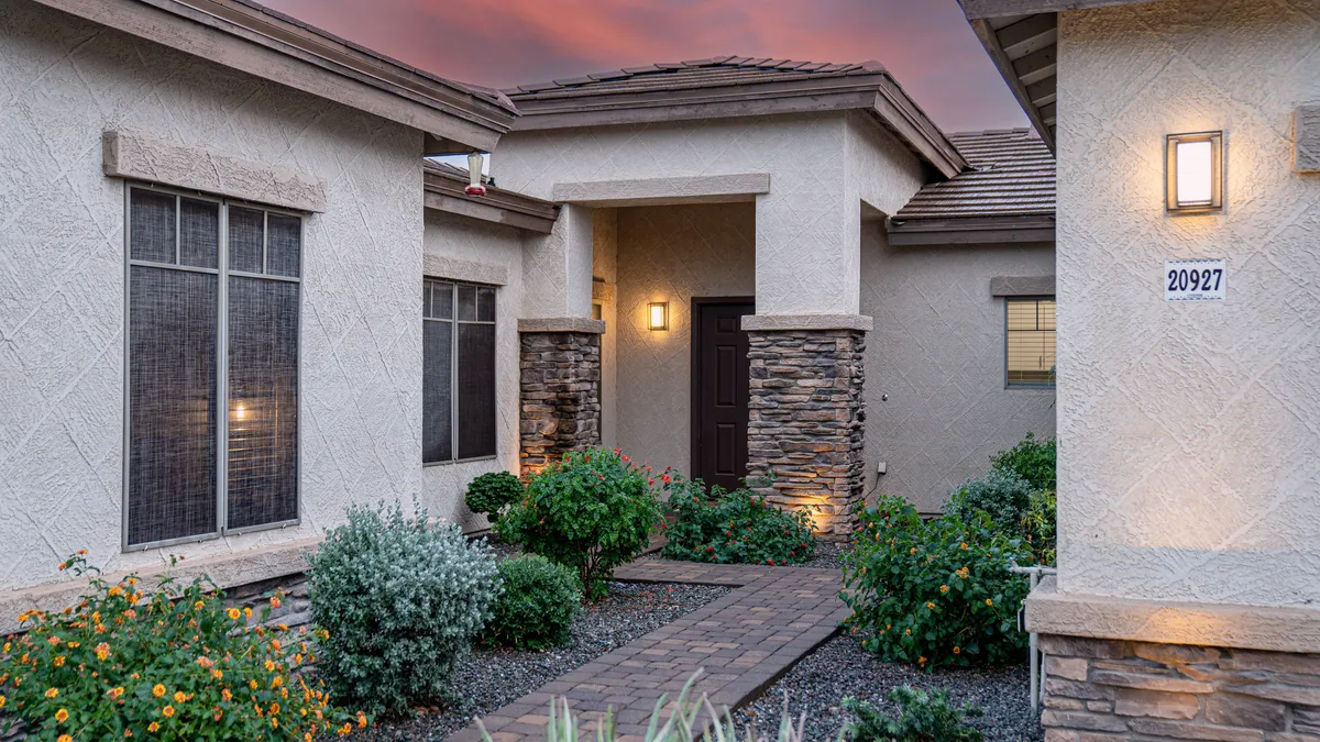 This exterior image features a landscaped pathway leading to a welcoming front door, surrounded by decorative stones and garden flowers. The scene evokes the feeling of stepping outside and enjoying the neighborhood environment.